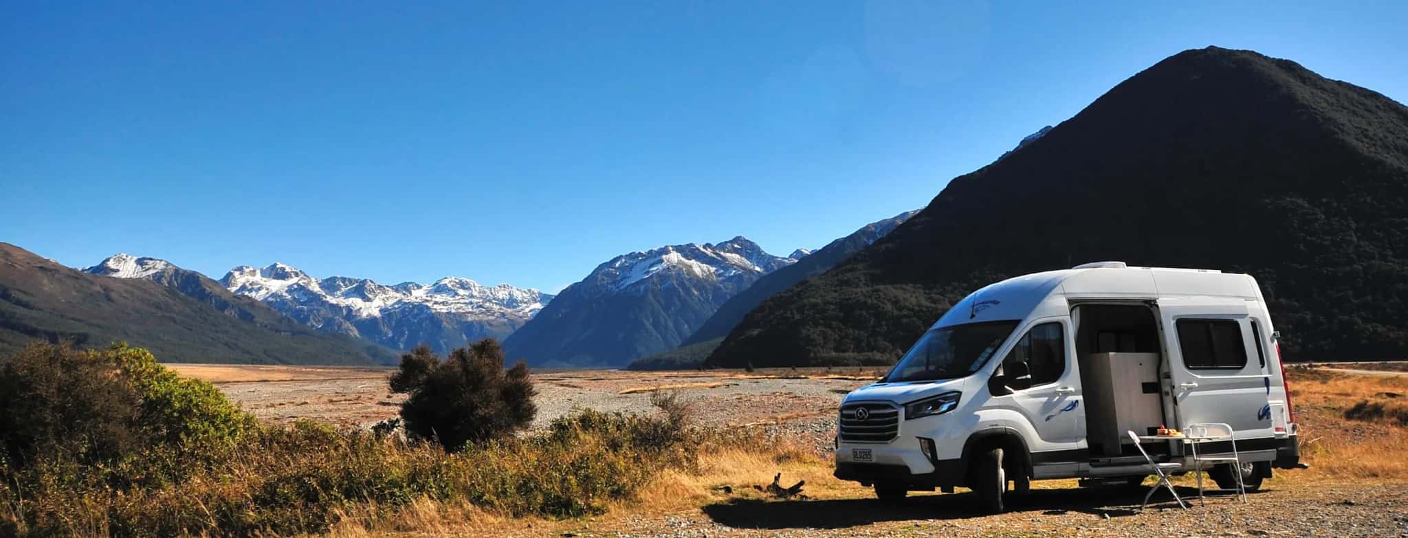 Wendekreisen Camper in Neuseeland vor schneebedeckten Bergen und weiter Landschaft.
