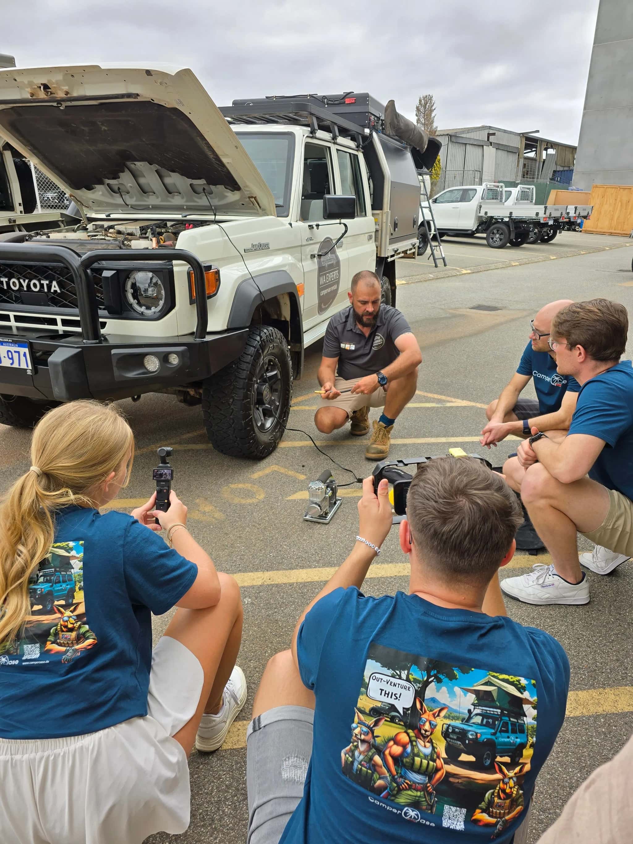 zwei Junge Kollegen am Filmen wie der Reifendruck am Allradcamper angepasst wird