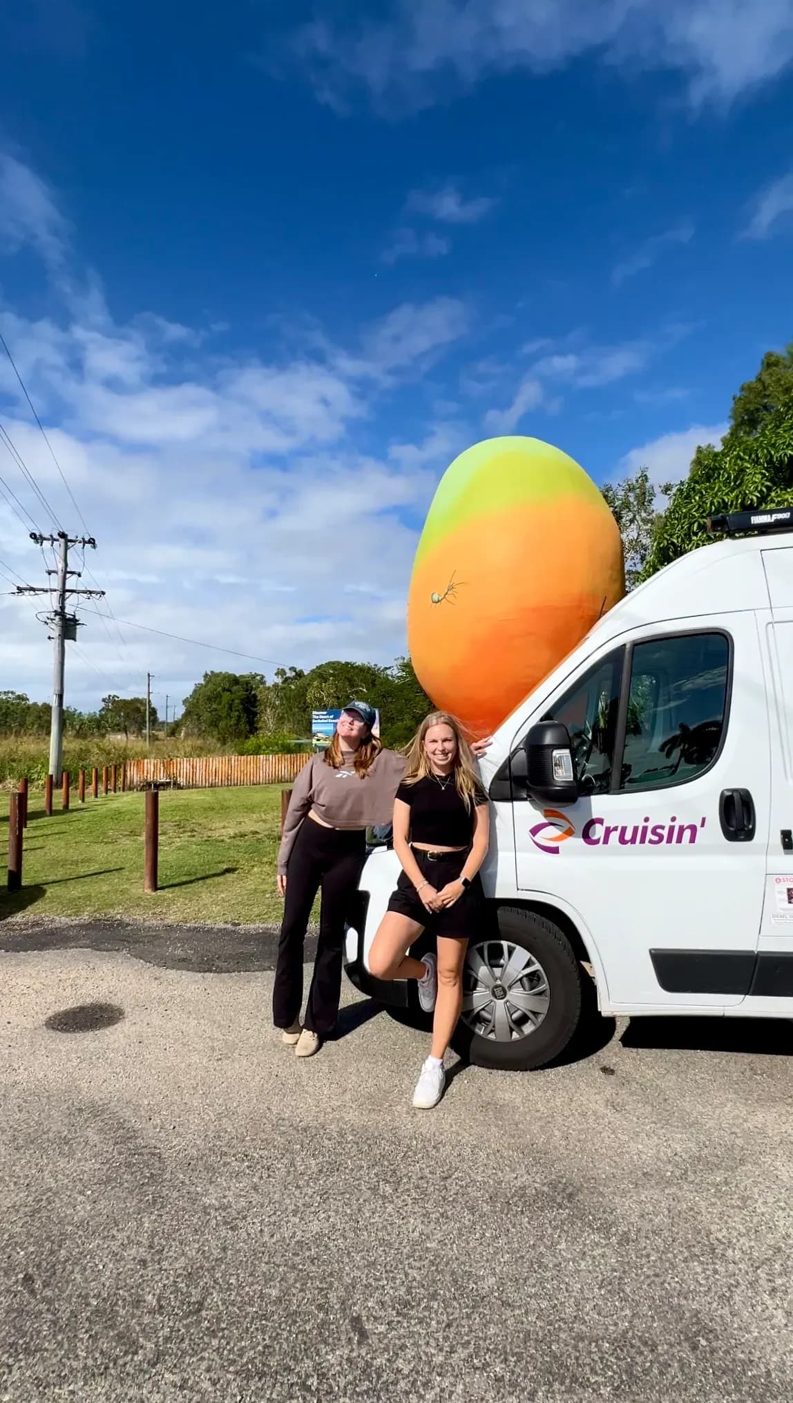 zwei junge Damen mit einem Camper vor der Big mango in Australien