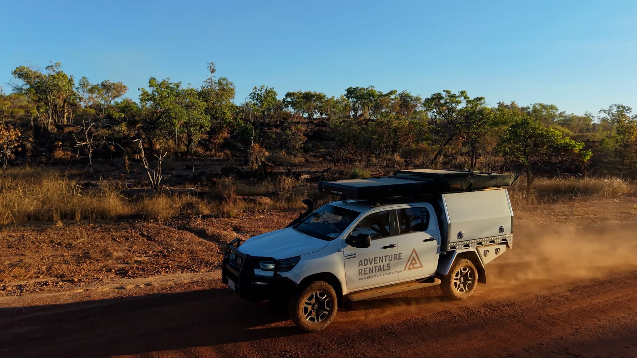 Weißer 4x4-Camper mit Dachzelt fährt auf einer roten Outback-Piste in Australien
