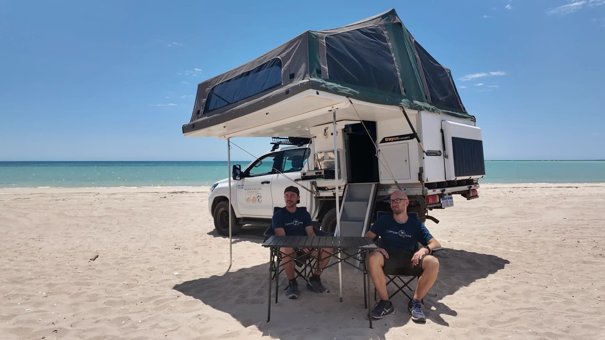 Allradcamper am Strand in Westaustralien mit aufgebauter Wohnkabine und zwei Herren, die in Stühlen davor sitzen