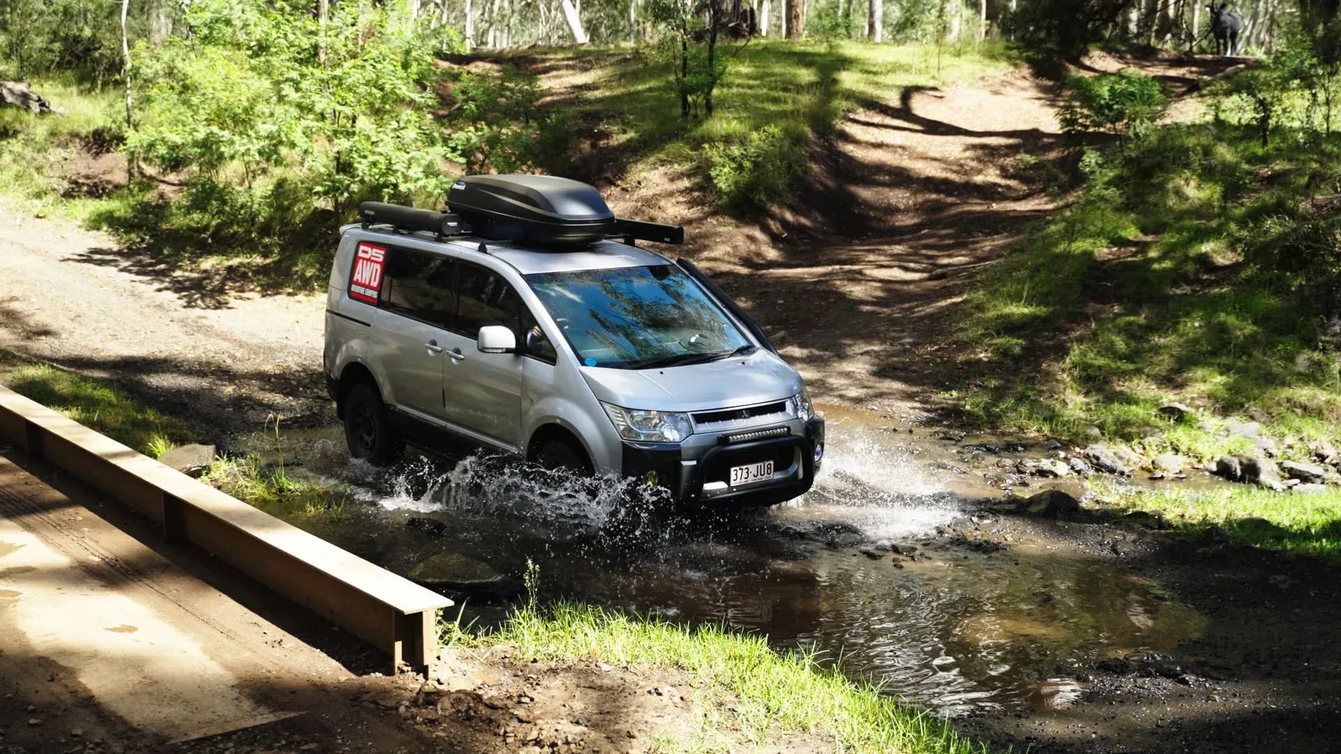Camper im Wald fährt durch Wasser