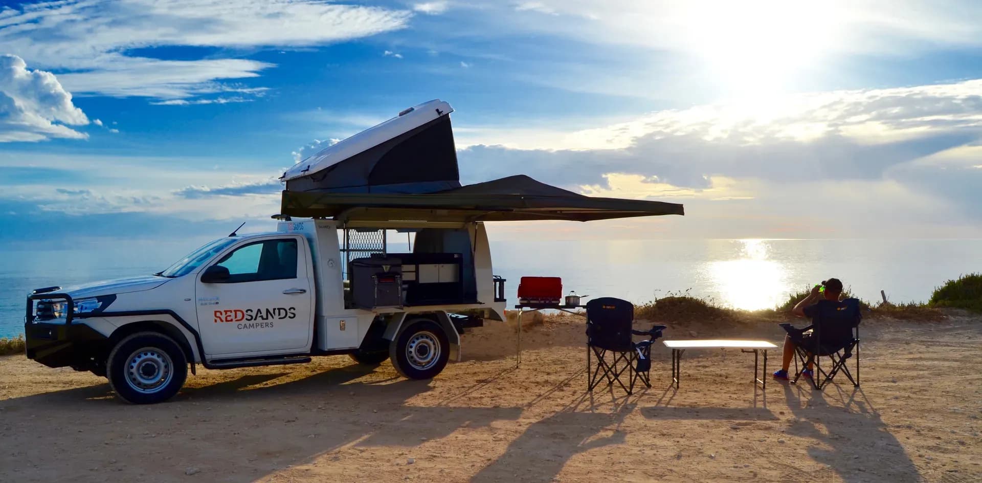 Camper mit Campingstühlen am Meer