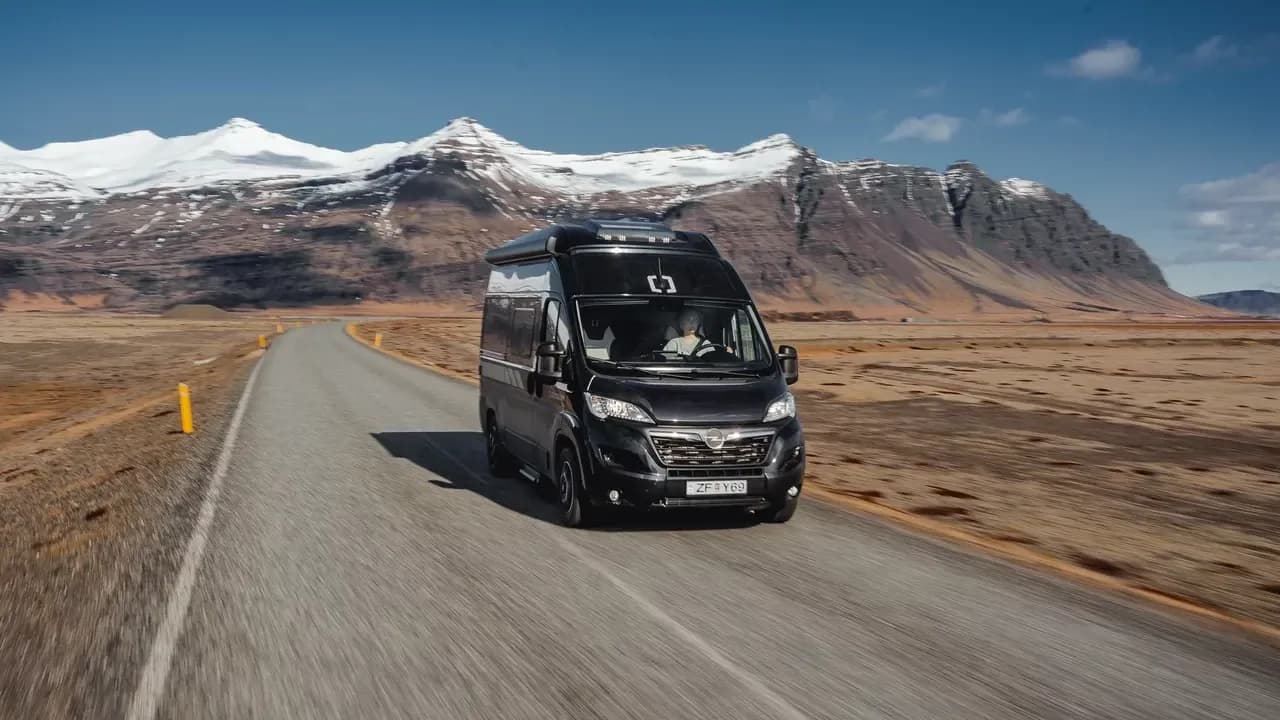 Crosscamp-Camper von Rent.is auf einer Straße vor schneebedeckten Bergen