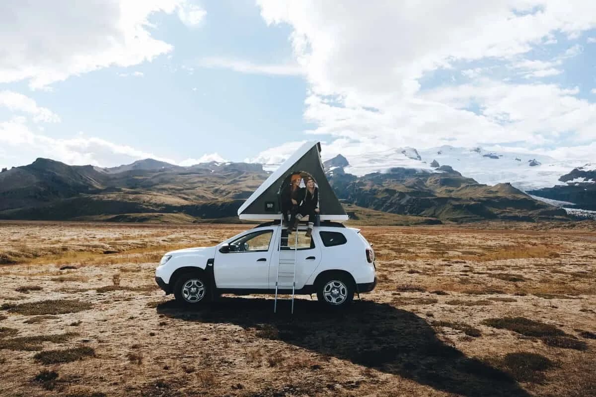 Rent.is Dacia Duster 4x4 mit geöffnetem Dachzelt vor Bergen