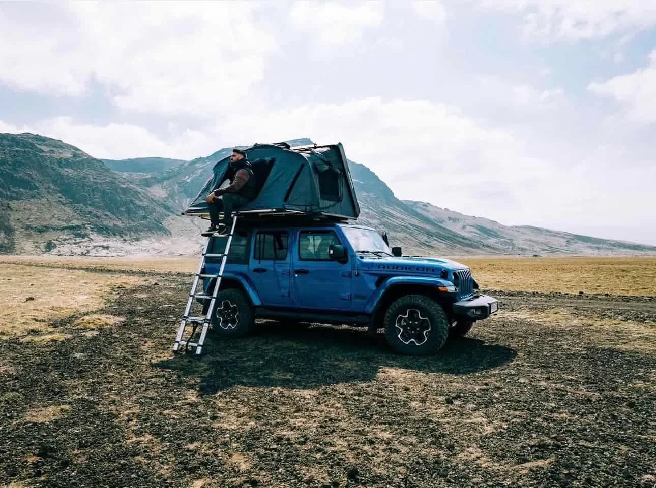 Person klettert ins geöffnete Dachzelt des Rent.is Jeep Wrangler 4xe