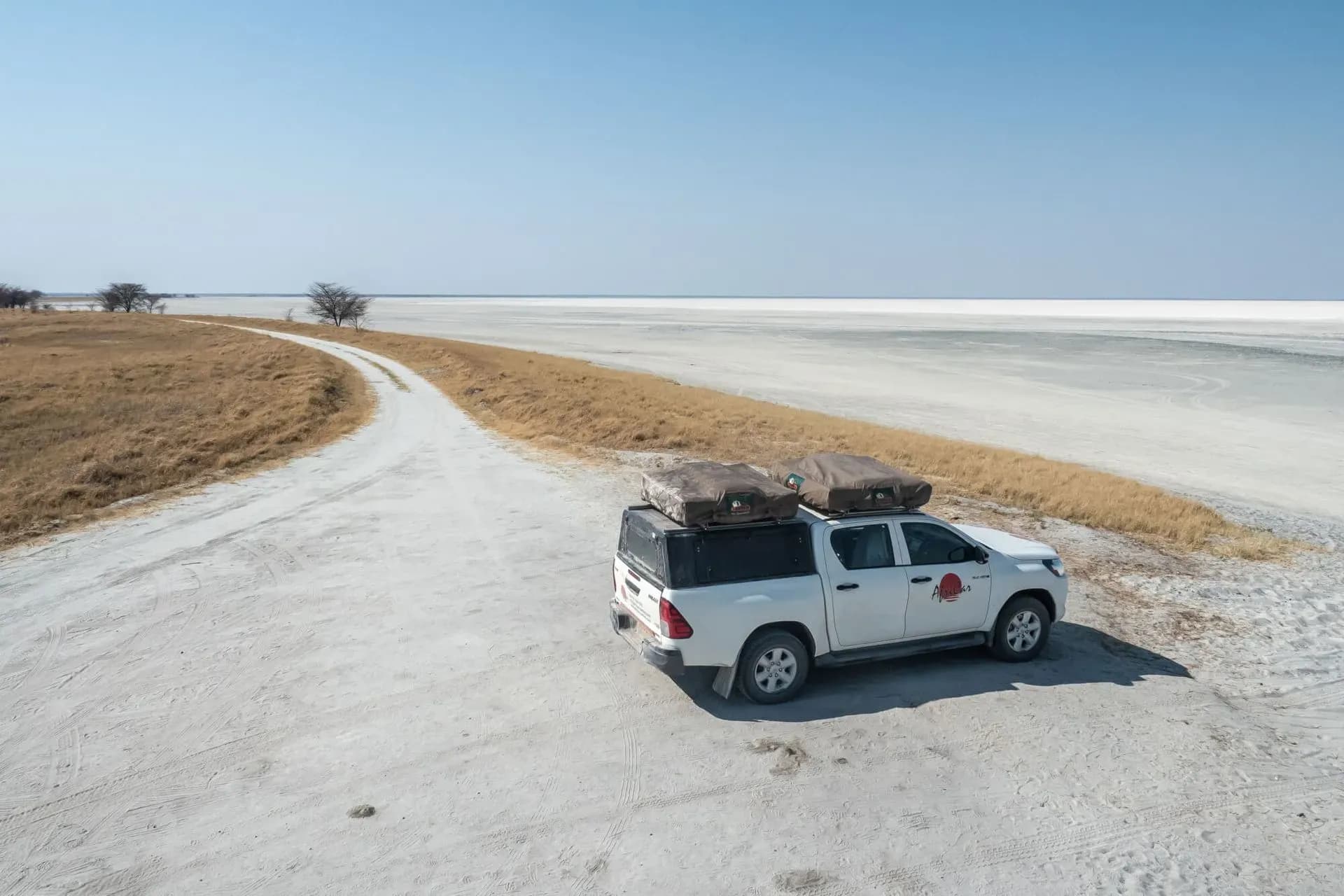 Der Budget Toyota Hilux 4 Pax von AfriCar Car Hire geparkt mitten in einer Sandlandschaft in Namibia