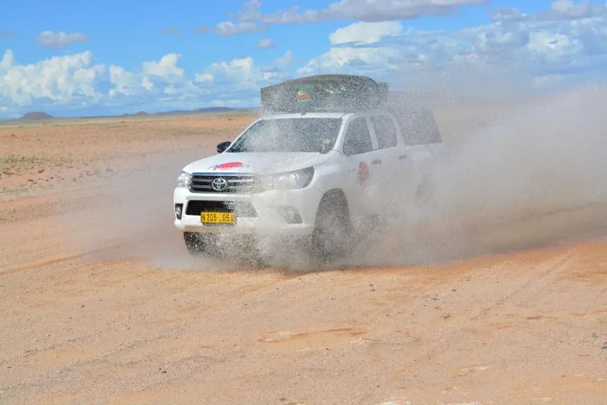 Der Premium Toyota Hilux 2 Pax von AfriCar Car Hire bei einer Offroad Durchfahrt auf Sand in Namibia