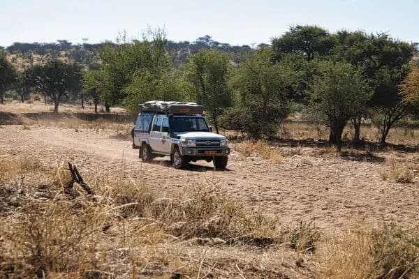 Toyota Landcruiser 4 Bett von AfriCar Car Hire in Namibia auf Sandstraße vor Bäumen
