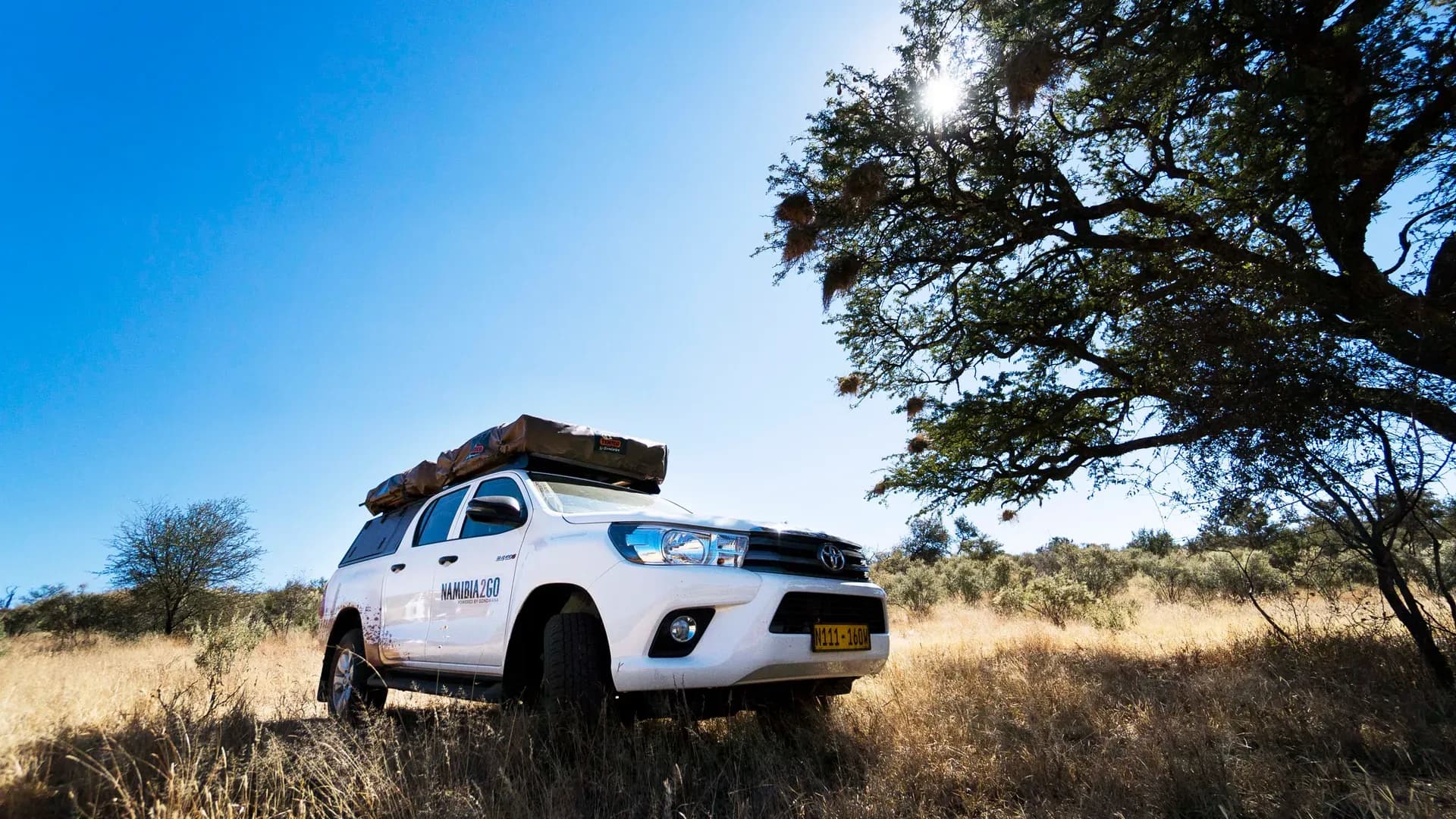 Toyota Hilux DC Camping Budget von Namibia2Go in trockener Graslandschaft in Namibia