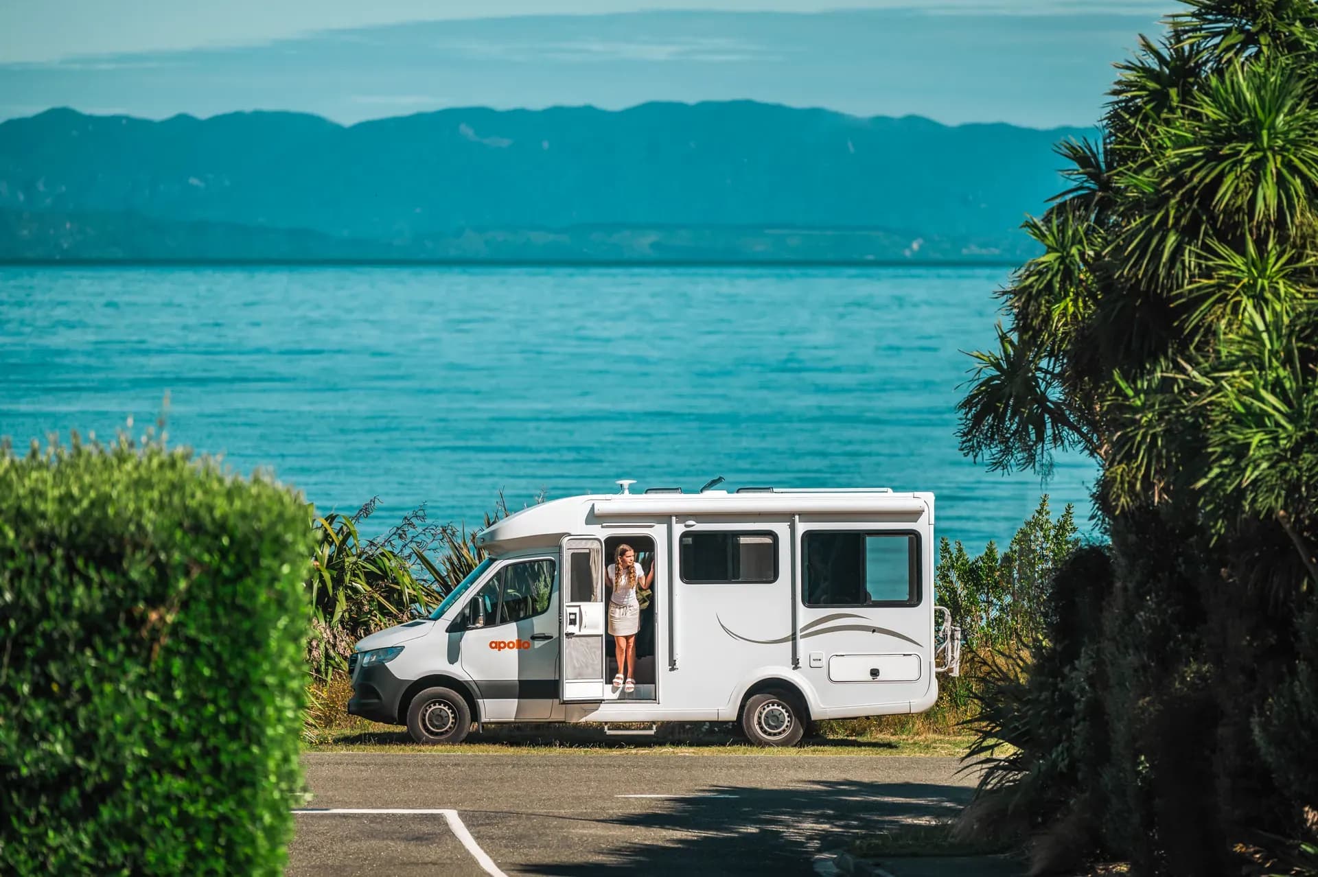 Euro Quest von Apollo Motorhomes mit offnener Tür vor See in Neuseeland
