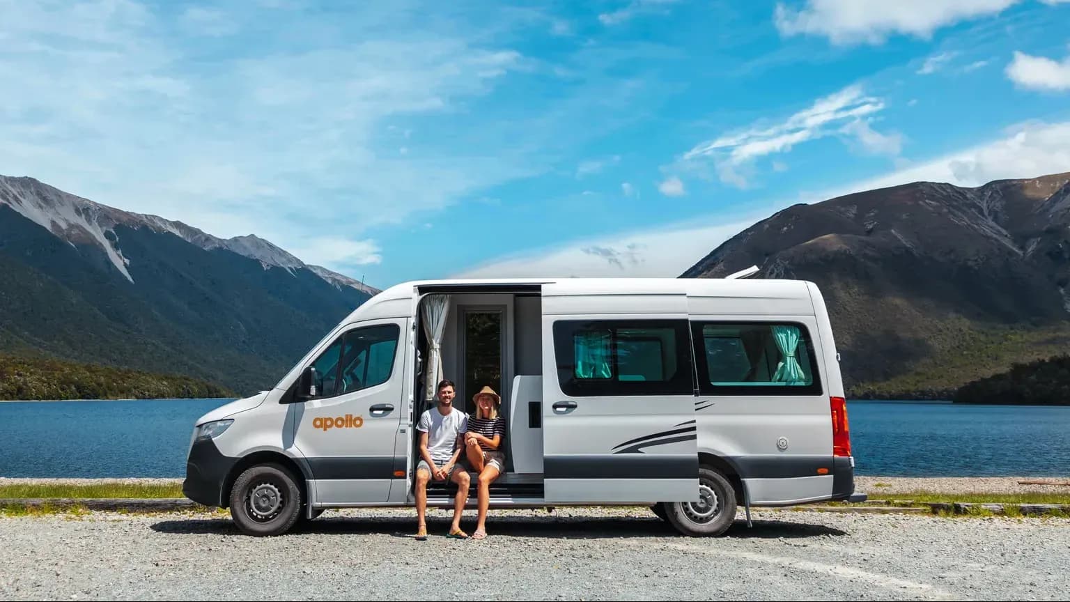 Euro Tourer von Apollo Motorhomes mit 2 Personen vor See mit Bergen in Neuseeland