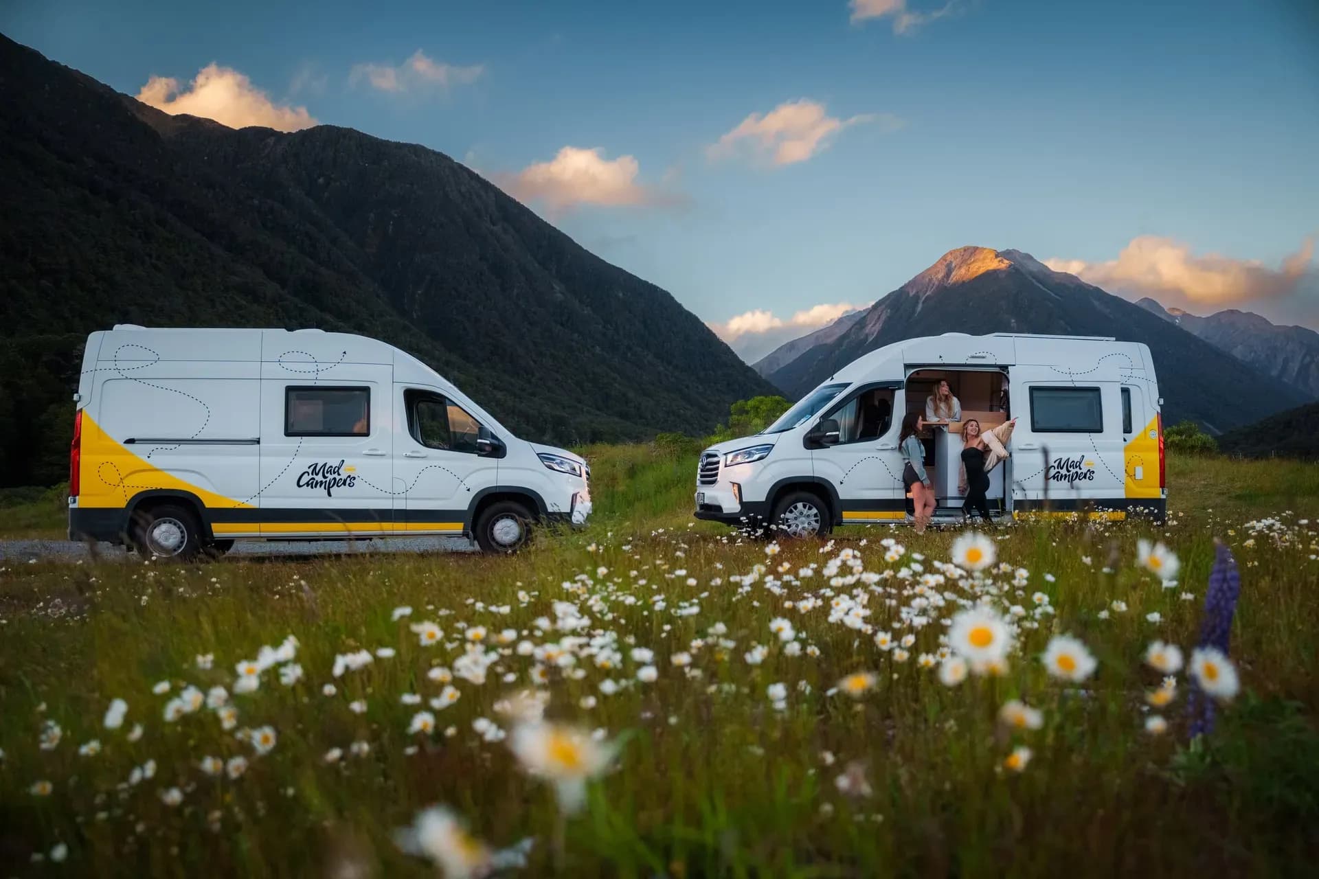 Zwei Mad Camper Explorer auf einer Wiese vor Bergen