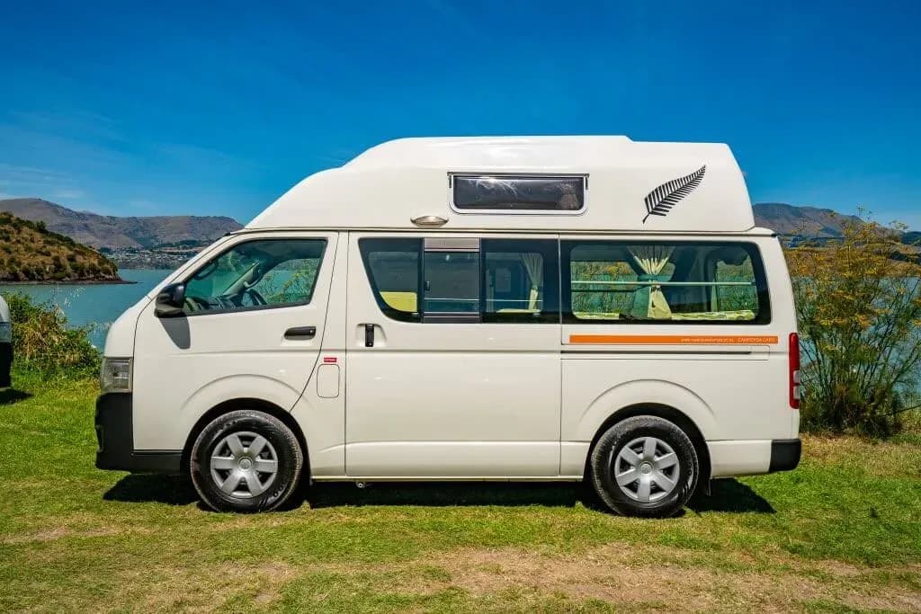 Queenie von Road Runner Rentals steht vor einem See in Neuseeland