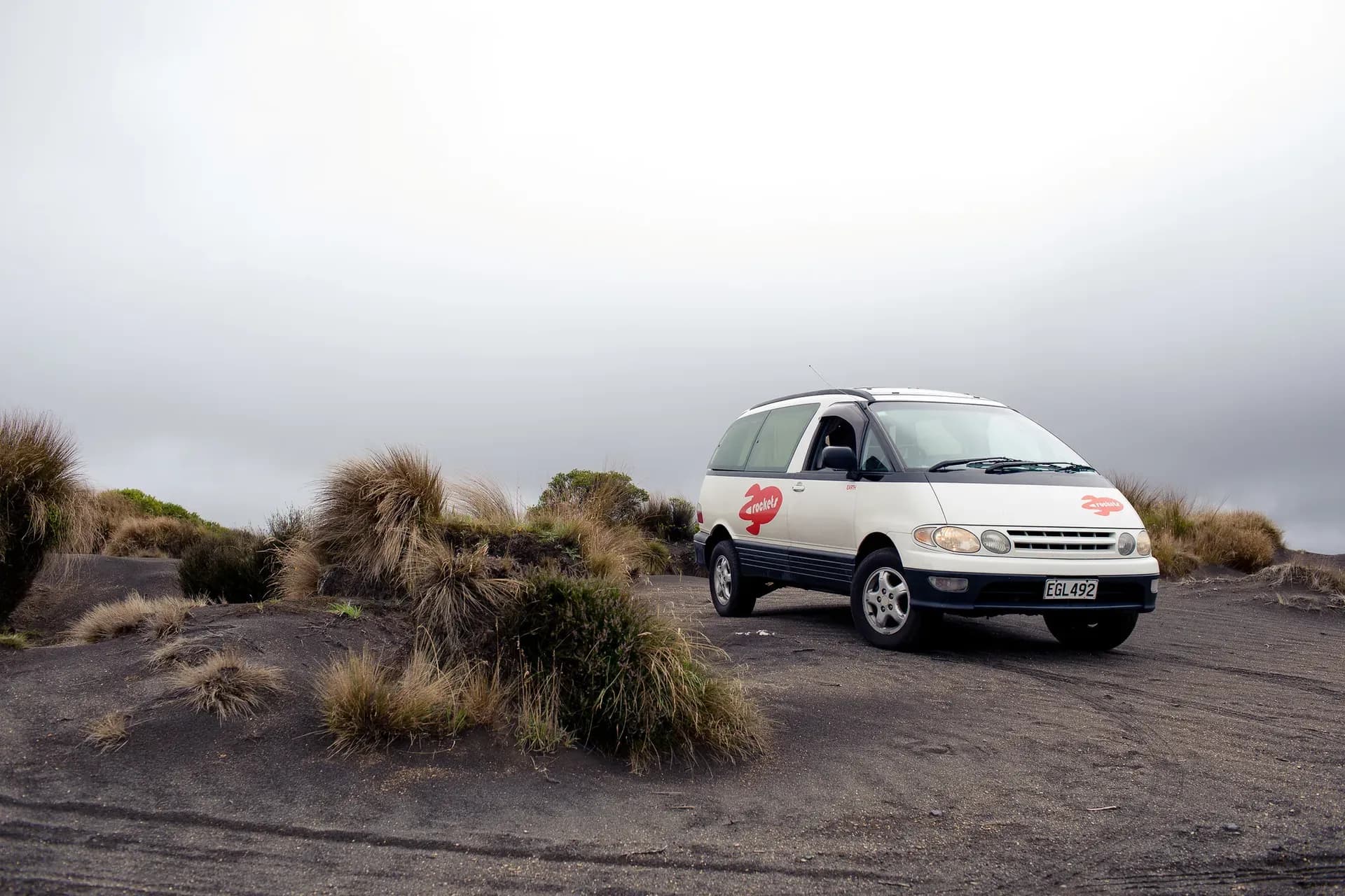 Der Rocket Sleeper Van von Spaceships für Backpacker, der auf ein Toyota Estima aufgebaut ist steht auf einem Sandstrand in Neuseeland