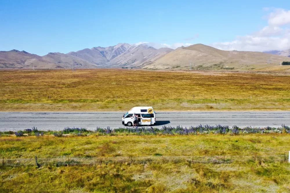 HI-TOP 2+1 Campervan von Travellers Autobarn auf Straße vor Bergen in Neuseeland