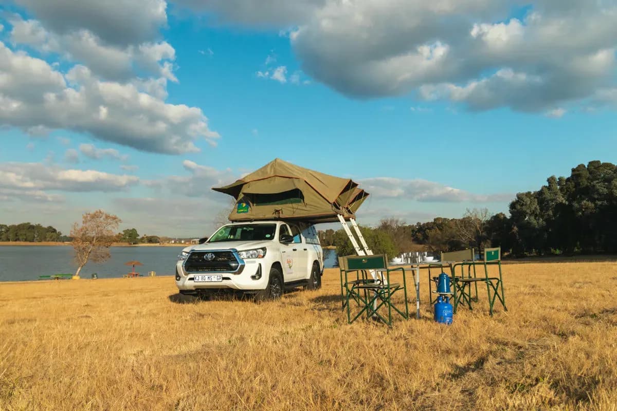 Der Toyota DOUBLE CAB 4 Pax von Britz Africa in Oase mit augebauten Zelten, Campingtisch und Stühlen.