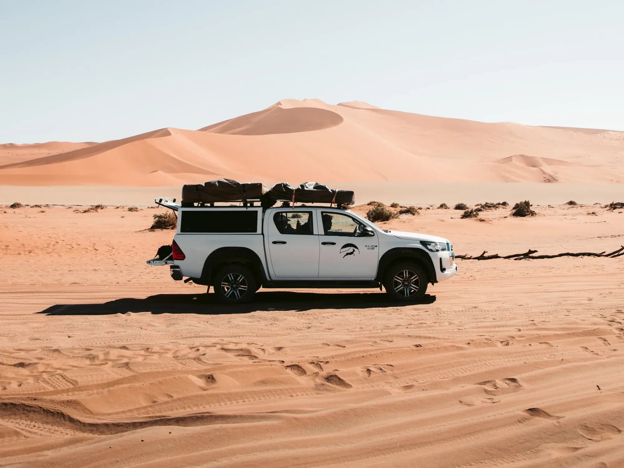 Weißer 4WD-Camper von Kalahari Car Hire vor Sanddünen in Namibia.