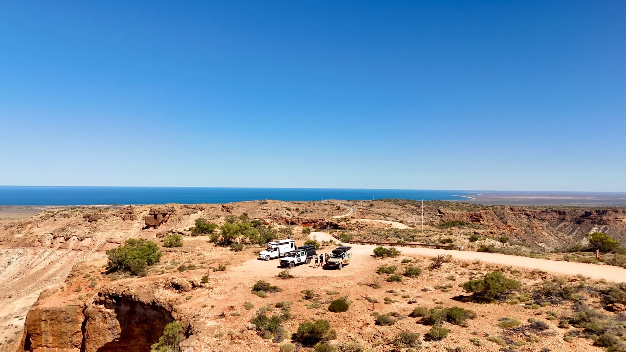 drei Allradcamper in felsiger Landschaft mit Meer im Hintergrund
