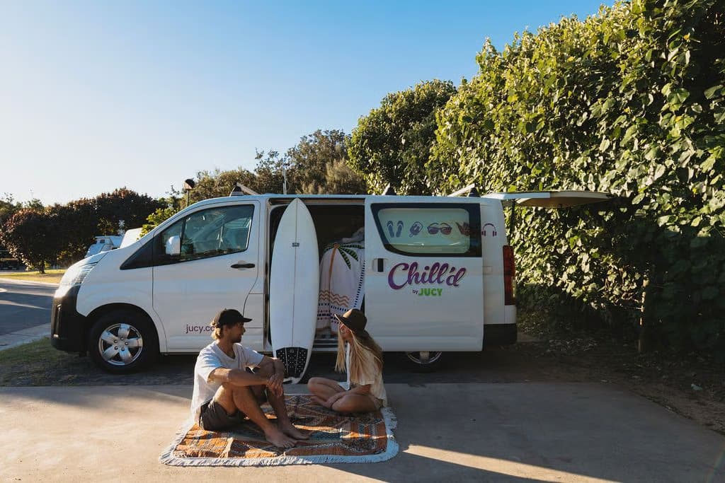 Der Chill'd Malibu von Jucy am Strand mit Surfbrett