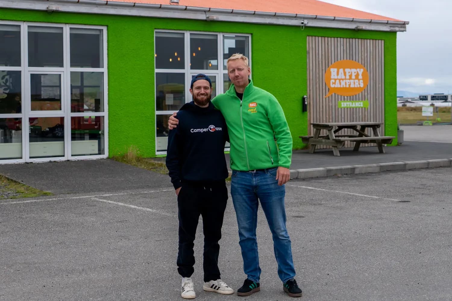 Vertreter von CamperOase und Happy Campers vor der grünen Mietstation von Happy Campers in Island.