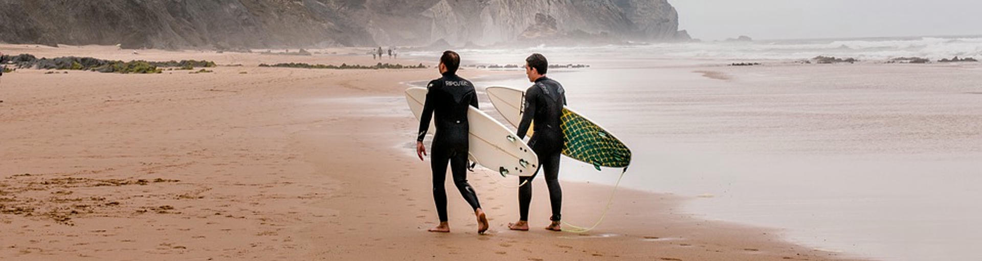 Zwei Surfer stehen in Portugal am Meer 